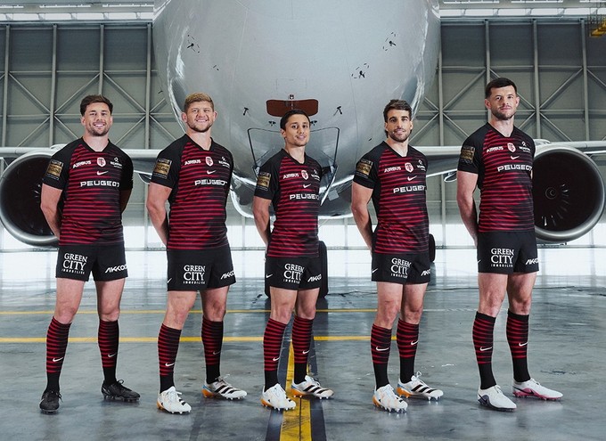 Spieler vor einem Airbus A330 Neo: Das Trikot ist traditionell rot-schwarz, aber mit Linien durchzogen, die «von den Kurven und aerodynamischen Strömungen inspiriert» sind.