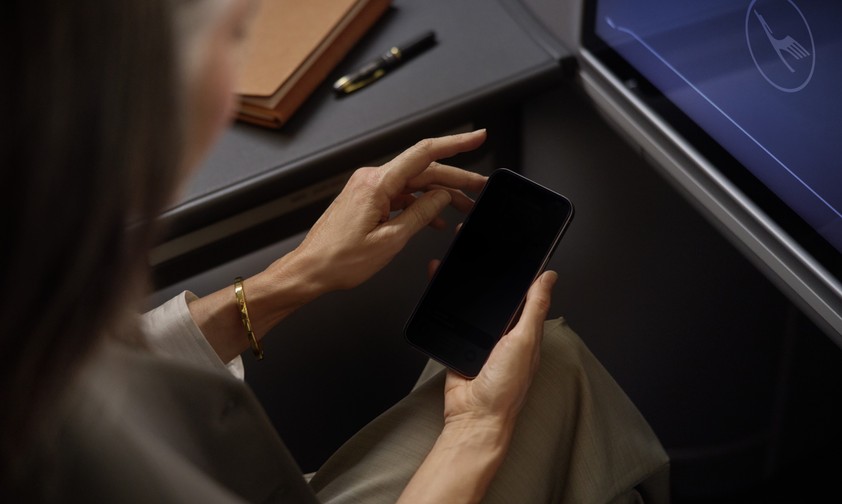 Lufthansa-Reisende hält ein Smartphone: Der Konzern wird alle 850 Flugzeuge mit Starlink ausstatten.