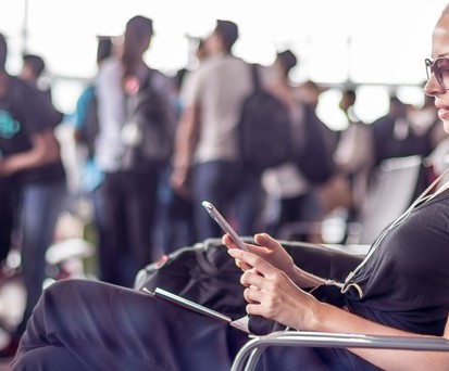 Frau mit Mobiltelefon am Flughafen: Das Wifi ist oft ein Grund für Ärger.