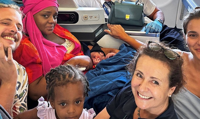 Frischgebackene Mutter mit ihren Baby und den Helfenden an Bord des A330-200.