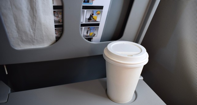 Kaffeebecher auf einem Flugzeugklapptisch: Einige Airlines verbieten jetzt das mitgebrachte Heißgetränk.