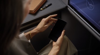 Lufthansa-Reisende hält ein Smartphone: Der Konzern wird alle 850 Flugzeuge mit Starlink ausstatten.