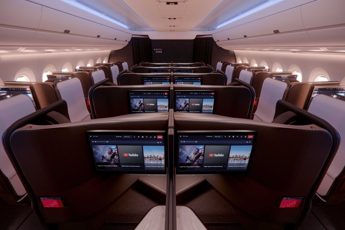 Die Business-Kabine mit Blick von hinten nach vorne und hervorgehobenen Bildschirmen.