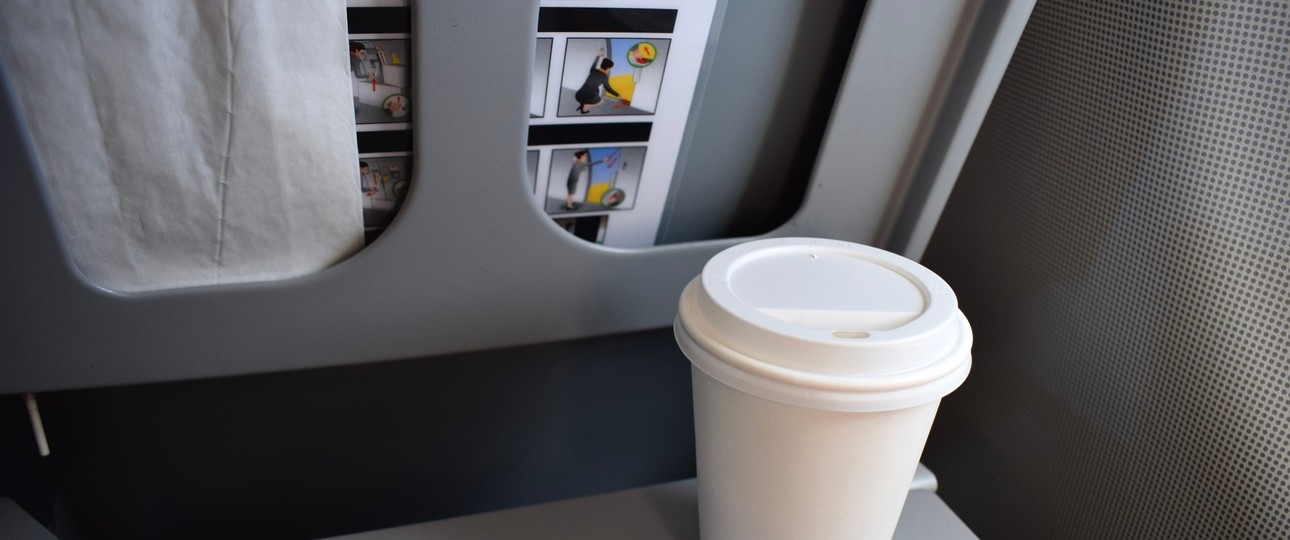 Kaffeebecher auf einem Flugzeugklapptisch: Einige Airlines verbieten jetzt das mitgebrachte Heißgetränk.