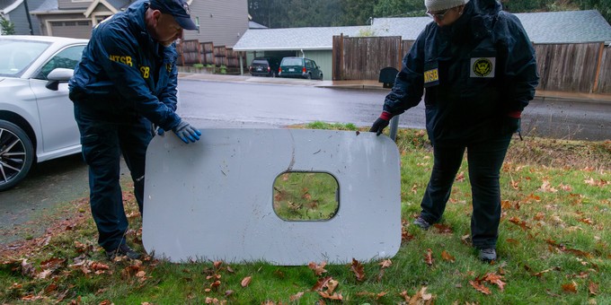 Zwei NTSB-Fachleute halten es hoch.