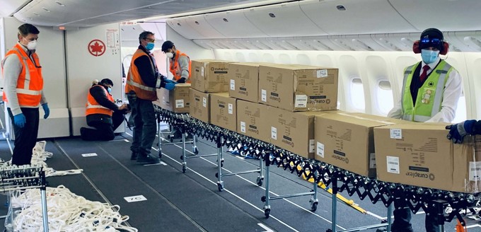 Auch in den Langstreckenfliegern entfernte Air Canada die Sitze, um zusätzliche Fracht laden zu können. Weil Systeme mit Bodenrollen üblicher Frachträume in Passagierkabinen fehlen, behelfen sich Bodenmitarbeiter mit einfachen Rollbändern.