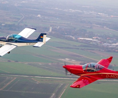 Zwei Breezer-Flugzeuge in der Luft: Das linke Flugzeug ist die erste Breezer aus dem Jahr 1999. Dahinter fliegt eine Breezer Sport.