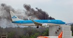Eine Maschine von KLM fliegt am brennenden Gebäude ...