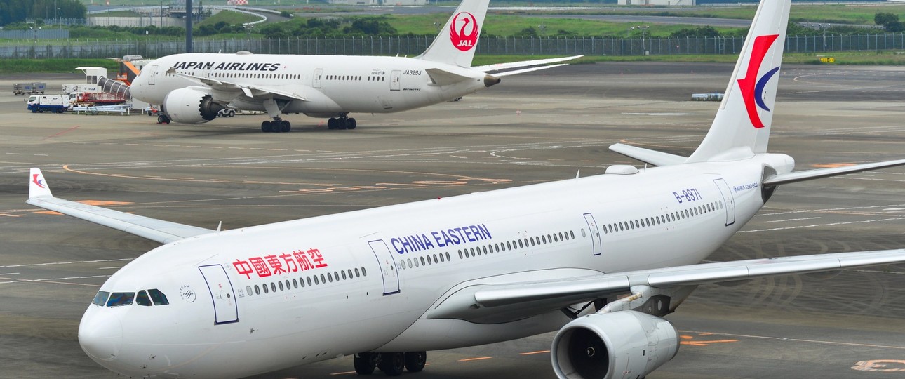 Airbus A330 von China Eastern, im Hintergrund steht ein Jet von Japan Airlines: Chinesische Fluglinien erleben derzeit eine Stornierungswelle für Japan-Flüge.