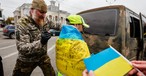 Ein Soldat unterschreibt die ukrainische Flagge, die ein Junge in Kherson trägt. Die ukrainische Armee wurde beim Einmarsch in Kherson freudig begrüßt.