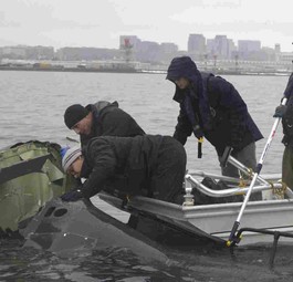 NTSB-Mitarbeiter an Wrackteilen im Potomac River: Untersuchung läuft.