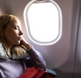 Eine Reisende schläft während des Fluges: Die App Timeshifter soll Jetlag reduzieren.