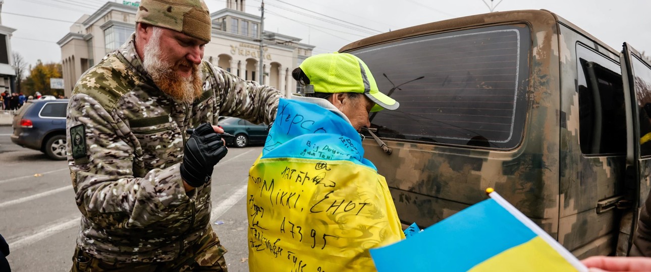 Ein Soldat unterschreibt die ukrainische Flagge, die ein Junge in Kherson trägt. Die ukrainische Armee wurde beim Einmarsch in Kherson freudig begrüßt.