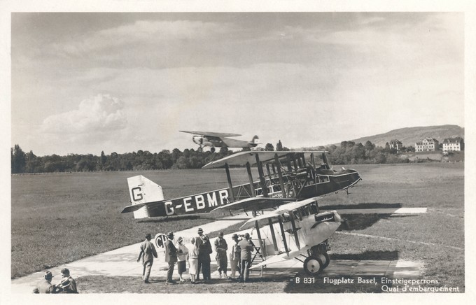 Ein wohl typischer Sommernachmittag auf dem Sternenfeld. Der Linienflug von Imperial Airways, durchgeführt mit der Handley Page W.10 G-EBMR, macht ihren Zwischenhalt in Basel. Mit der Caudron C.59 CH-125 der Aviatik beider Basel werden vermutlich Rundflüge durchgeführt. Eingestiegen wird über eine Bockleiter, bei laufendem Motor. Im Hintergrund startet eine Fokker F.VII der KLM, aufgrund anderer Aufnahmen vermutlich die H-NADN (später PH-AND).