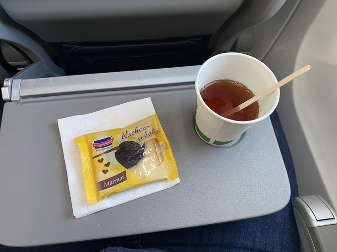 Kleine Verpflegung auf dem kurzen Flug: ein Getränk und eine gesponserte Kuchenscheibe.
