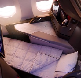 Ein Sitz der Delta One Suite im A350-1000 als Bettmodus mit Decke