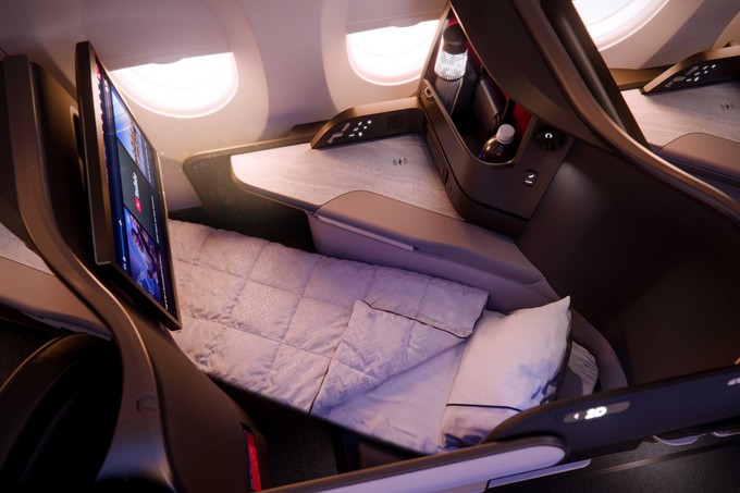 Ein Sitz der Delta One Suite im A350-1000 als Bettmodus mit Decke.