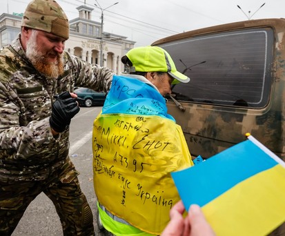 Ein Soldat unterschreibt die ukrainische Flagge, die ein Junge in Kherson trägt. Die ukrainische Armee wurde beim Einmarsch in Kherson freudig begrüßt.