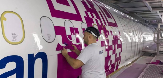 Ein Mitarbeiter klebt den QR-Code auf die Maschine.