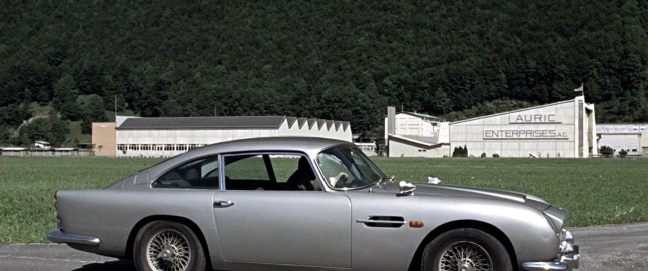 James Bond und sein Aston Martin vor der Goldschmelze von Auric Goldfinger.