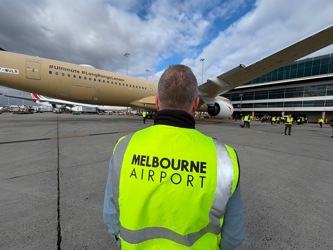 Ein Mitarbeitender des Flughafen Melbourne vor dem Flugzeug am Gate.