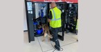 Hund und Hundeführer beschnüffeln einen Getränkeautomaten:  Sie machen den BER sauber.