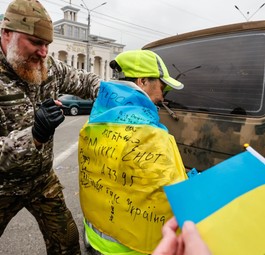 Ein Soldat unterschreibt die ukrainische Flagge, die ein Junge in Kherson trägt. Die ukrainische Armee wurde beim Einmarsch in Kherson freudig begrüßt.