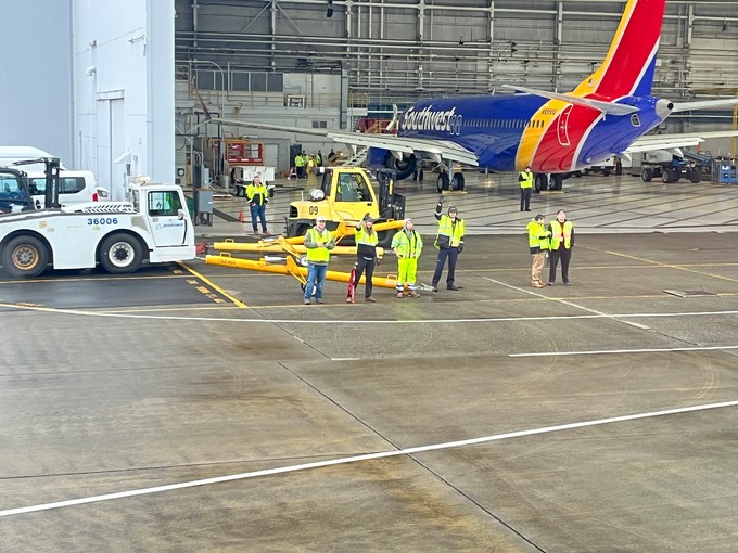 Winkende Boeing-Mitarbeitende verabschieden die G-TUPE vor dem Abflug nach Manchester.