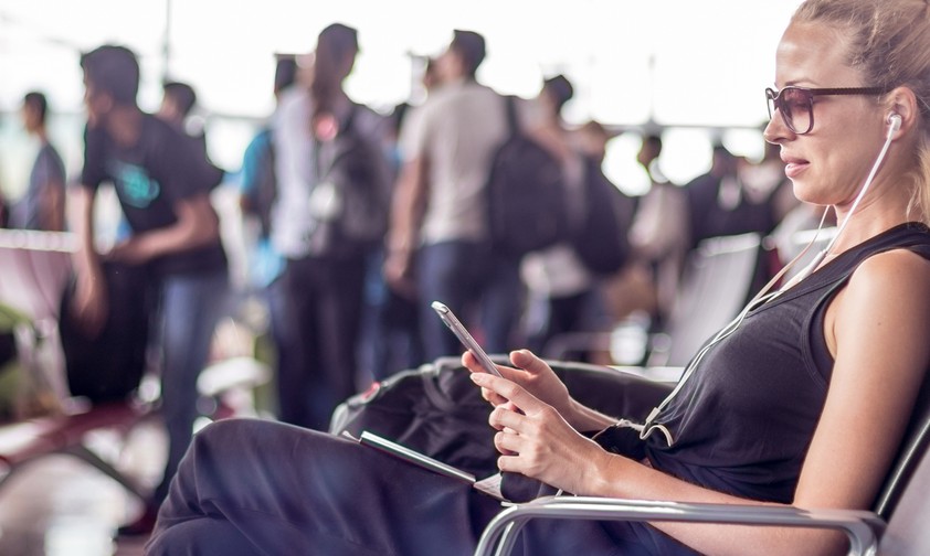 Frau mit Mobiltelefon am Flughafen: Das Wifi ist oft ein Grund für Ärger.