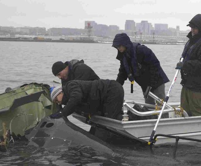 NTSB-Mitarbeiter an Wrackteilen im Potomac River: Untersuchung läuft.
