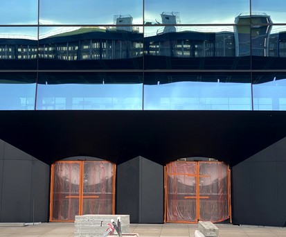 Parkhaus spiegelt sich in Fassade: Einer der Eingänge zur großen Halle ...
