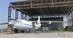 Verlassen steht eine Antonov An-12 vor einem ehemaligen Hangar. Beide rosten vor sich hin.