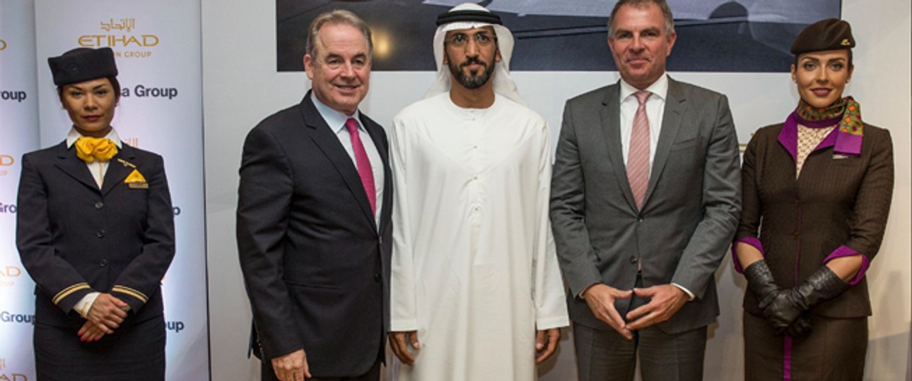 Etihad-Lenker James Hogan (l.), Etihad-Vorstand Mohamed Mubarak Al Mazrouei (M.),  Lufthansa-Chef Carsten Spohr (r.) mit zwei Flugbegleiterinnen nach Unterzeichnung des Abkommens.