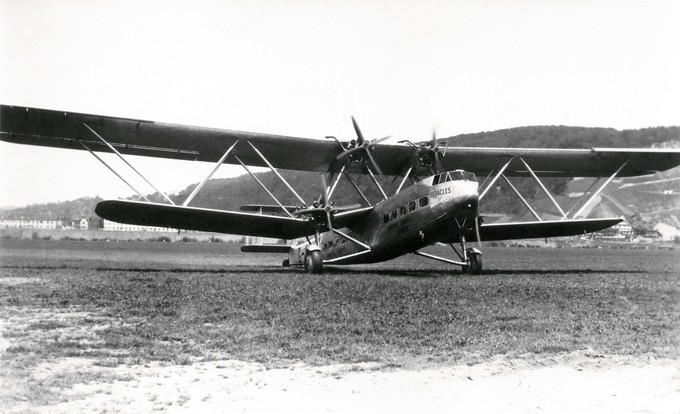 Handley-Page HP-42 Heracles. Im Hintergrund der Hornfelsen, der jenseits des Rheins in Deutschland liegt. Der HP-42 war das damals grösste Passagierflugzeug. Zwar fliegt der Heracles nur 160 Kilometerm in der Stunde, dies jedoch mit fast 40 Passagieren und gutem Komfort, also typisch british. Der Doppeldecker ist in Ganzmetall-Bauweise hergestellt. Nur die Beplankung der Tragflächen ist noch in Sperrholz gefertigt. Die G-AAXC ist die erste von vier Maschinen der «Western» Serie der H.P.42, nach vier bereits gelieferten Maschinen der auf Langstrecken verwendeten «Eastern» Serie. Am 19. März 1940 wird die «Heracles» auf dem Flugfeld von Whitchurch, Somerset (UK) durch einen Sturm umgedreht und irreparabel beschädigt.