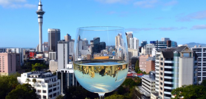 62.309 Liter Sauvignon Blanc. Ein Glas des Weins ist hier vor der Skyline von Auckland zu sehen.