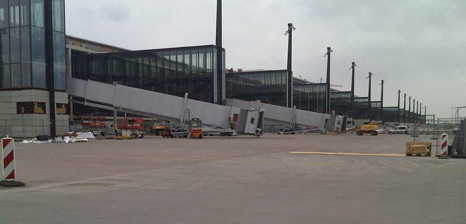 Montage der ersten Fluggastbrücken im Juli 2011: Bereits im Vorjahr wurde der Eröffnungstermin vom 30.Oktober 2011 auf den 3. Juni 2012 verlegt. Im Winter 2011 wurden erste Probleme um die Brandschutzanlagen bekannt - es folgte eine jahrelange Pannenserie.