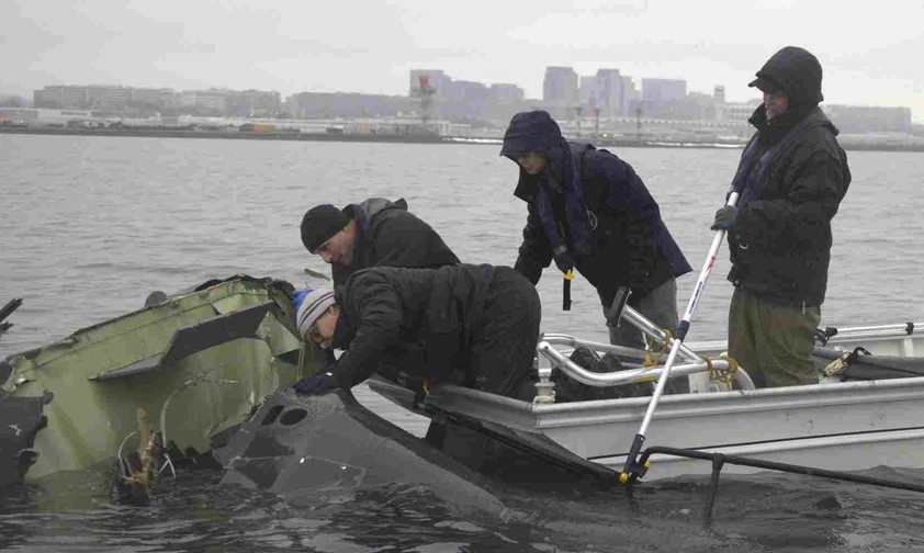 NTSB-Mitarbeiter an Wrackteilen im Potomac River: Untersuchung läuft.