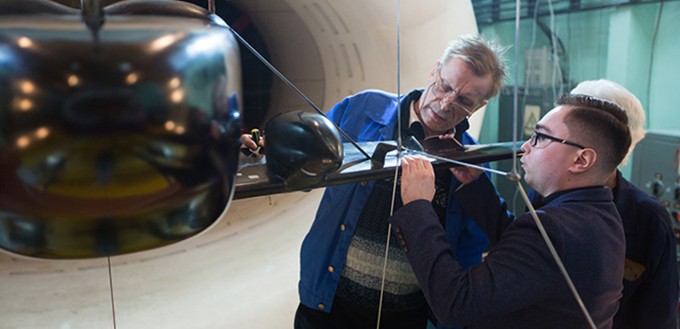 Forscher des Tsagi schauen sich ein Modell des neuen Fliegers an. Sie ...