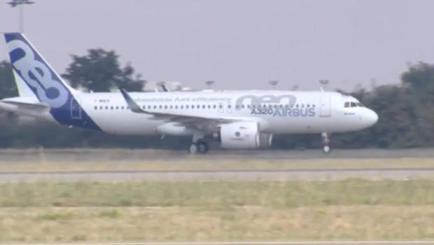Man sieht es nur schemenhaft: Die Piloten winken mit einer Airbus-Fahne aus dem Cockpit.