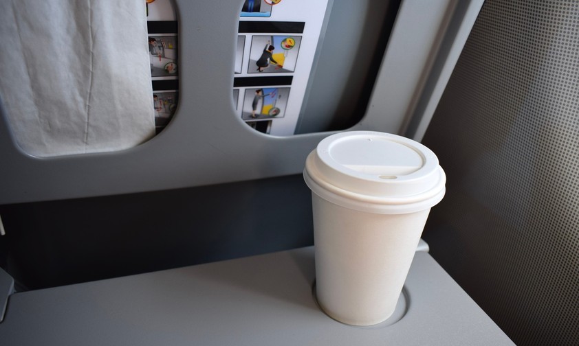 Kaffeebecher auf einem Flugzeugklapptisch: Einige Airlines verbieten jetzt das mitgebrachte Heißgetränk.