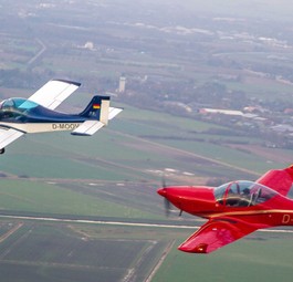 Zwei Breezer-Flugzeuge in der Luft: Das linke Flugzeug ist die erste Breezer aus dem Jahr 1999. Dahinter fliegt eine Breezer Sport.