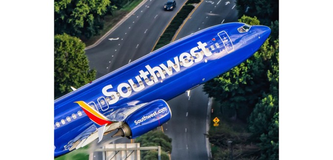 Boeing 737-800 von Kapitän Ted Orris beim Abschiedsflug: Die Aufnahme wurde aus einem Hubschrauber fotografiert, in die Kamera winkt Orris' Kopilot.