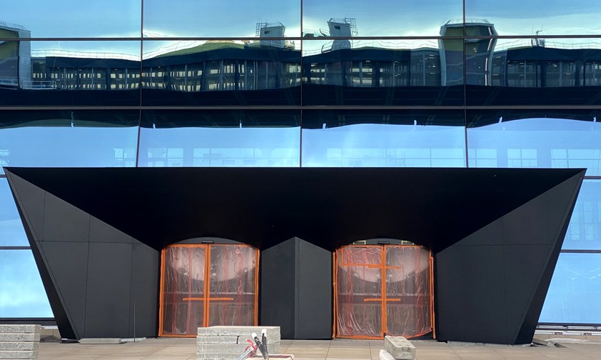 Parkhaus spiegelt sich in Fassade: Einer der Eingänge zur großen Halle ...
