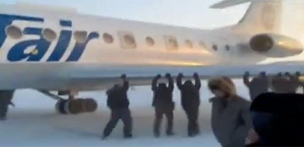 Passagiere packen mit an: Die Tu-134 wurde aus dem Eis befreit.