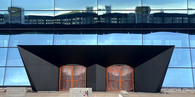 Parkhaus spiegelt sich in Fassade: Einer der Eingänge zur großen Halle ...