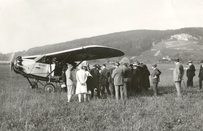 Modisch «behutet» stehen die Rundflug­gäste und Zuschauer der Aviatik beider Basel beim Flugzeug, bei laufendem Motor der Comte AC-8 CH-280.