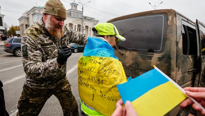 Ein Soldat unterschreibt die ukrainische Flagge, die ein Junge in Kherson trägt. Die ukrainische Armee wurde beim Einmarsch in Kherson freudig begrüßt.