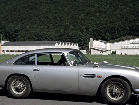 James Bond und sein Aston Martin vor der Goldschmelze von Auric Goldfinger.