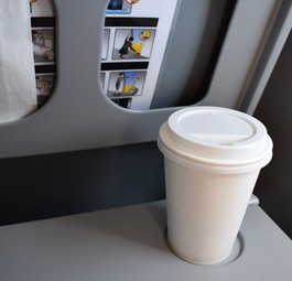 Kaffeebecher auf einem Flugzeugklapptisch: Einige Airlines verbieten jetzt das mitgebrachte Heißgetränk.