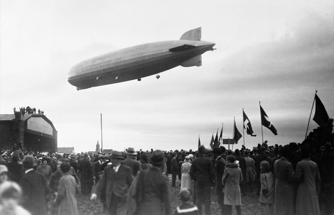 Alle sind sie gekommen auf das Sternenfeld, um den angekündigten Graf Zeppelin zu erleben, ein 236,6 Meter langes Starrluftschiff aus der Produktion der Luftschiffwerft in Friedrichshafen. Im Hintergrund der auf dem Basler Euro Airport noch immer existierende und in Betrieb stehende Lucky-Strike-Hangar.